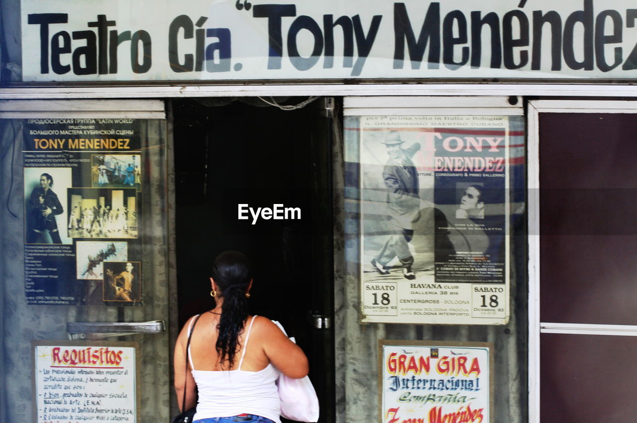 REFLECTION OF MAN AND WOMAN STANDING BY STORE