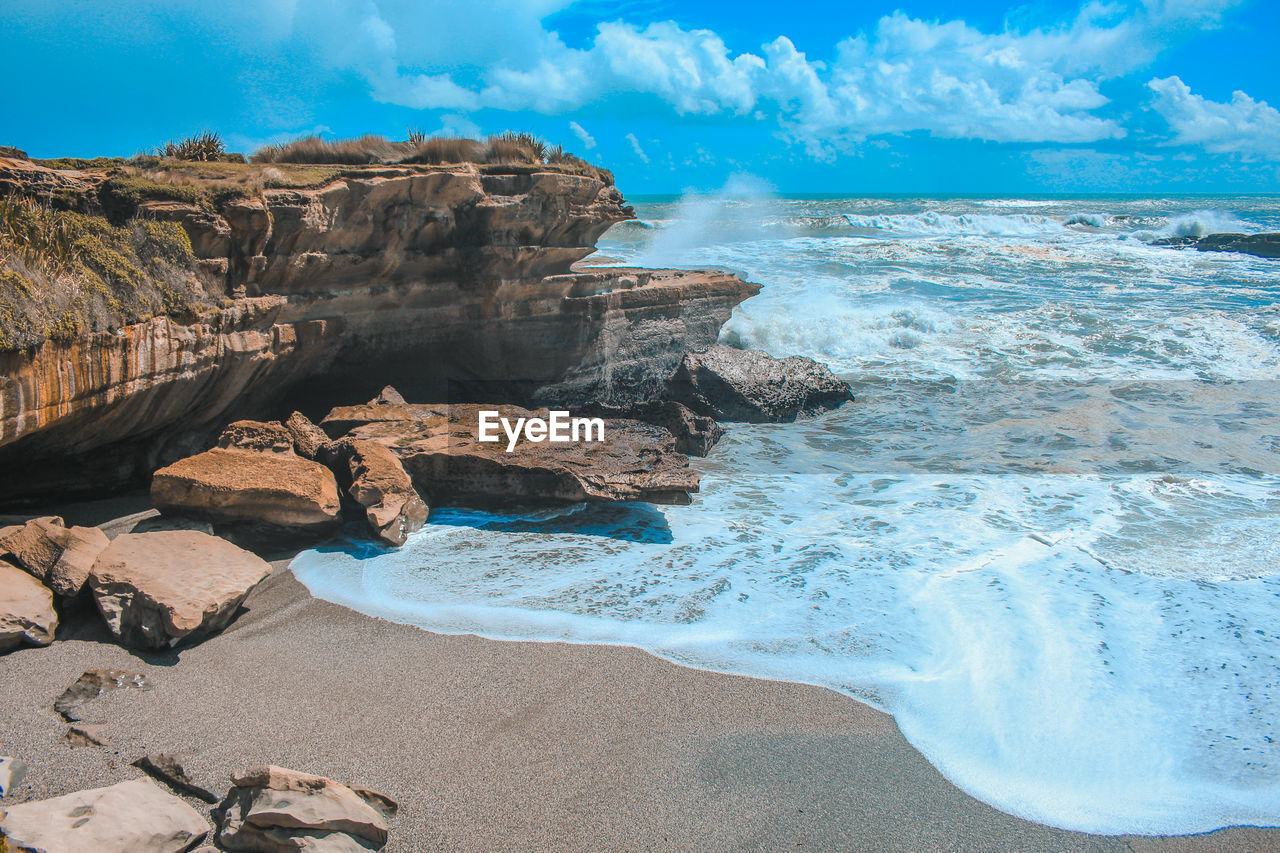 Scenic view of rock formation on beach against sky