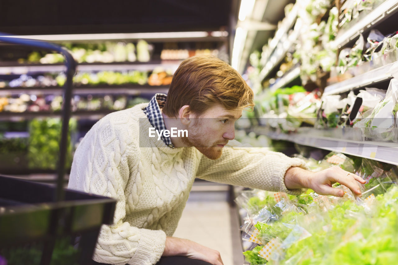 Young man shopping vegetables at supermarket