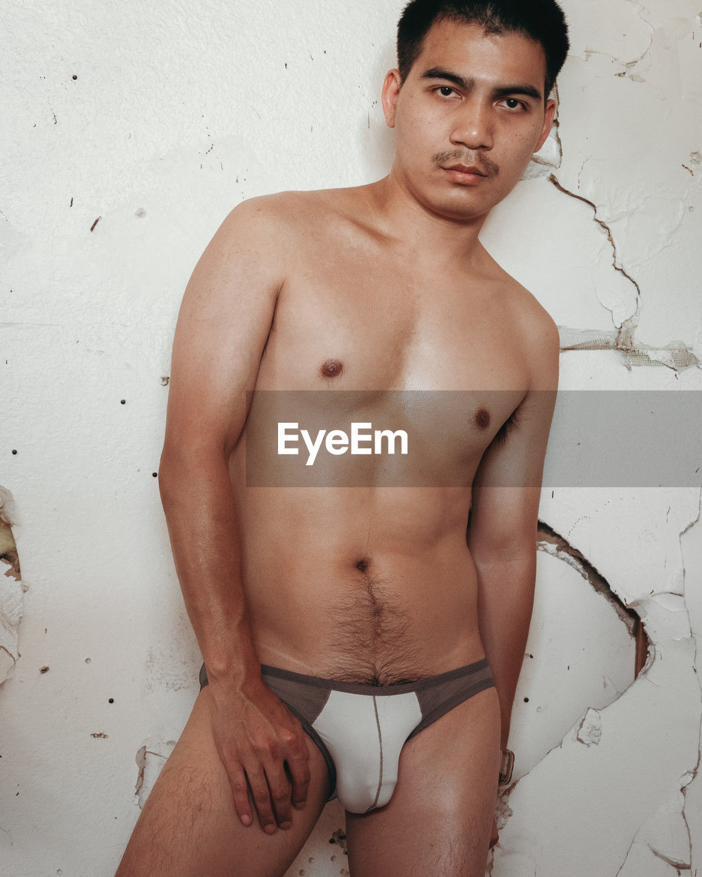 men, barechested, young adult, one person, portrait, adult, muscular build, underpants, looking at camera, person, standing, briefs, serious, lifestyles, wall - building feature, indoors, fashion, strength, clothing, studio shot, undergarment, three quarter length
