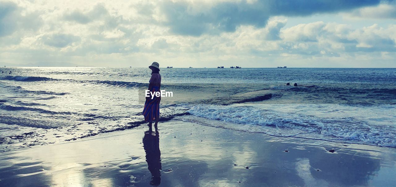 WOODEN POSTS ON BEACH AGAINST SKY