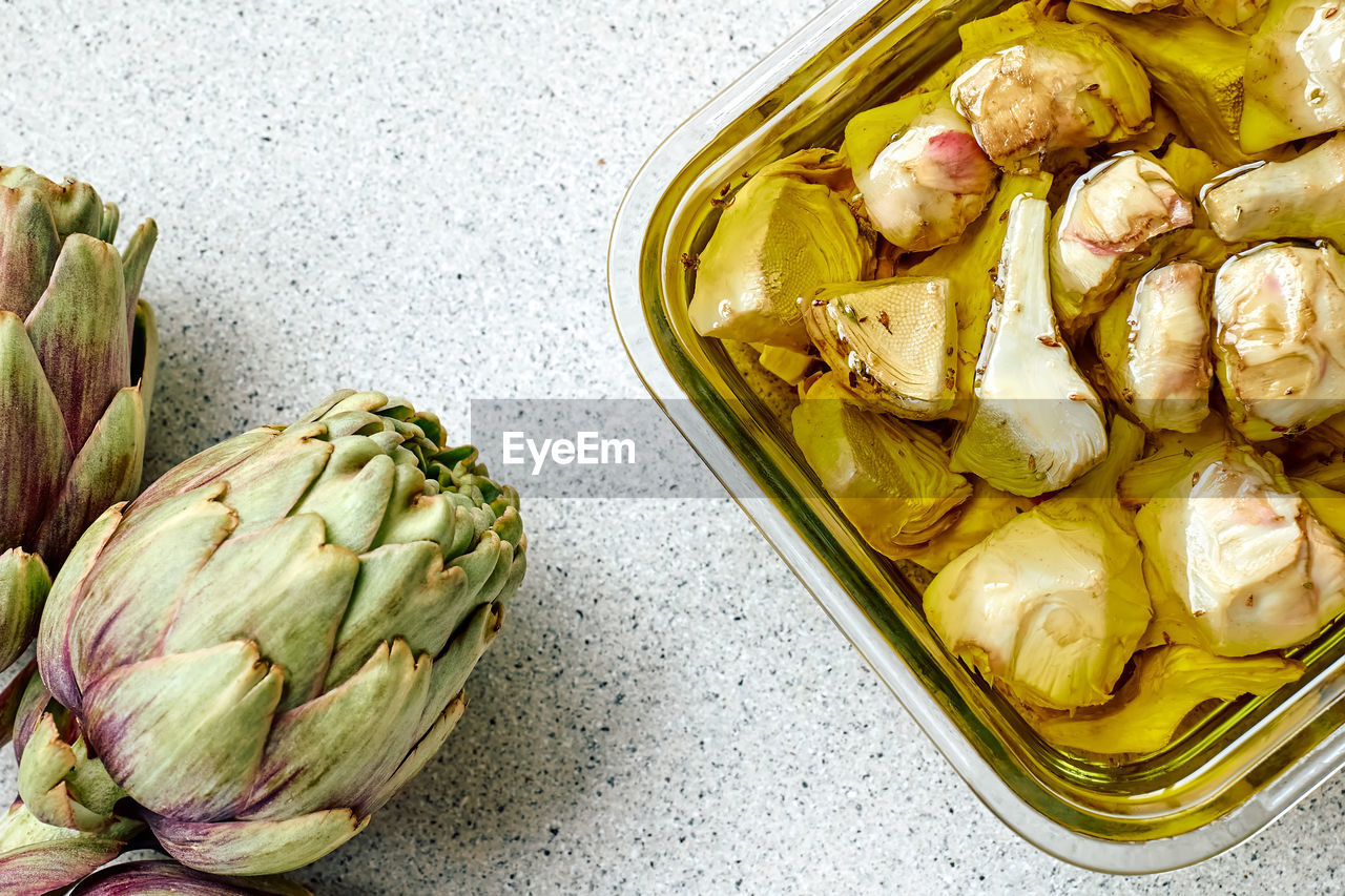 Artichokes hearts marinated with olive oil and herbs. pickled artichoke with garlic in glass bowl. 