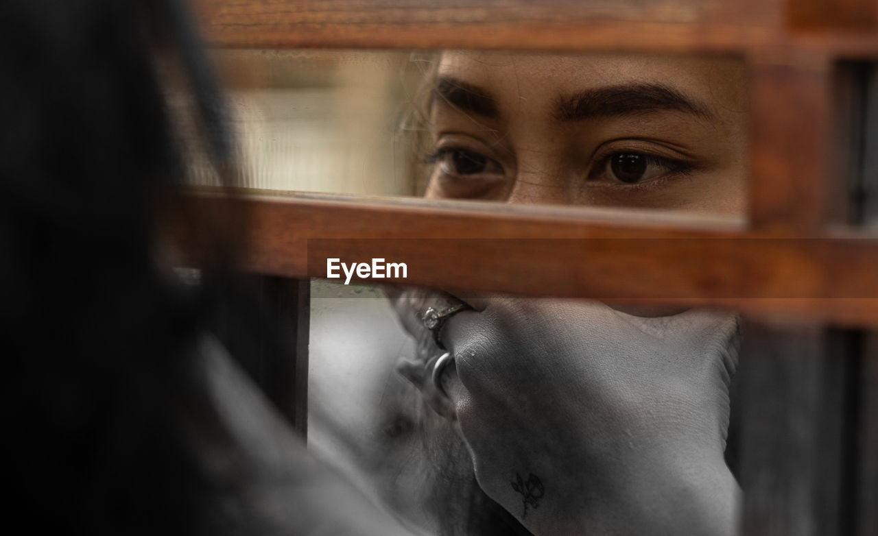 Close-up portrait of young woman looking through window