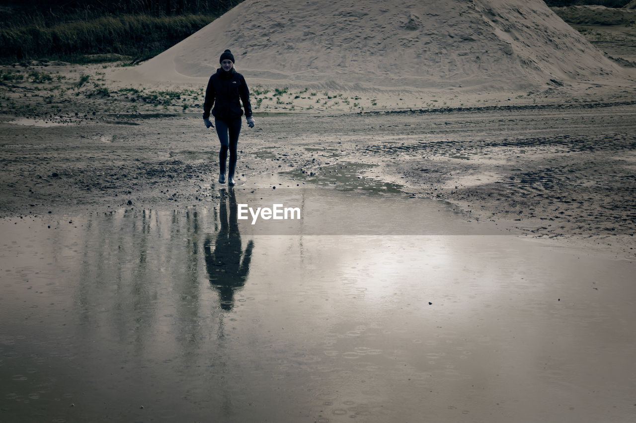 Reflection of young woman in pond during winter