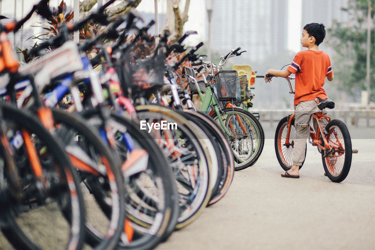 Rear view of boy cycling on road in city