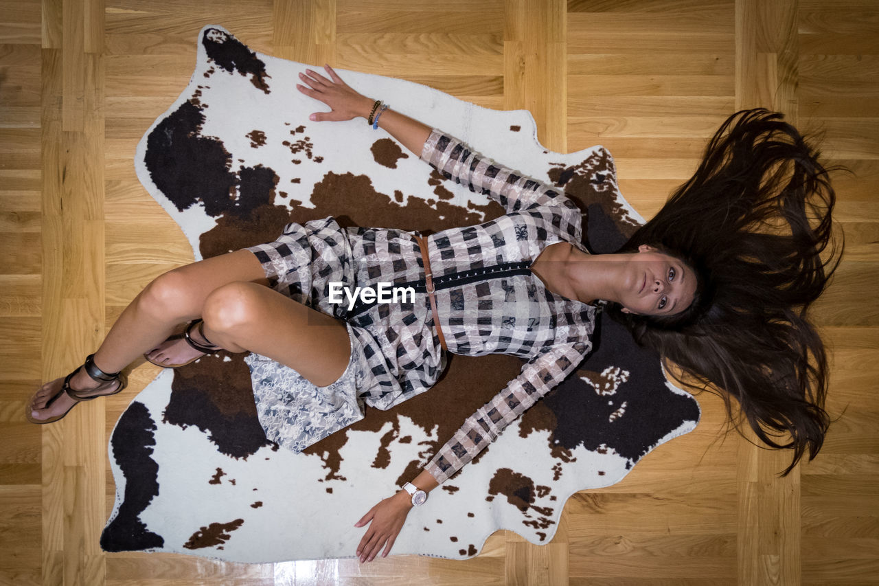 High angle view of woman lying on hardwood floor at home