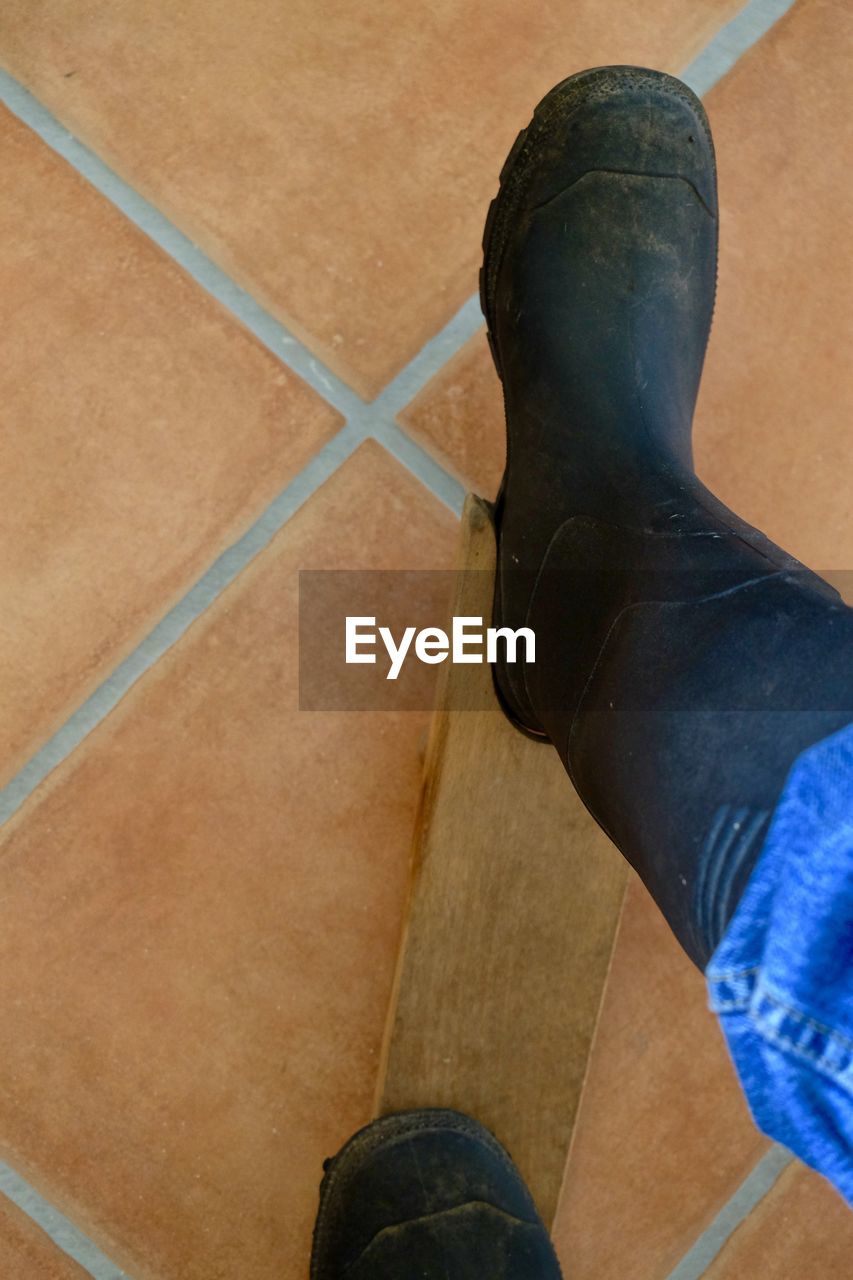 LOW SECTION OF WOMAN STANDING ON HARDWOOD FLOOR