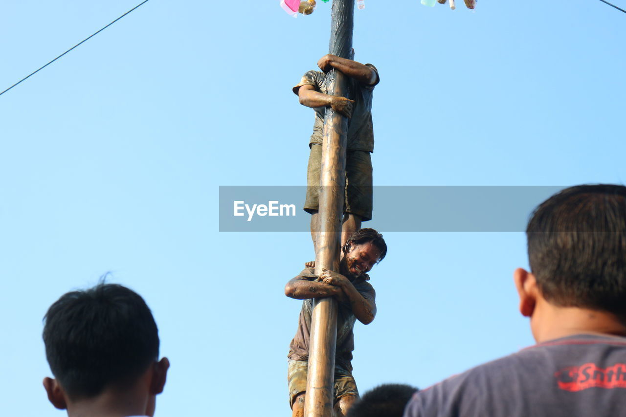 REAR VIEW OF PEOPLE ENJOYING AGAINST CLEAR SKY