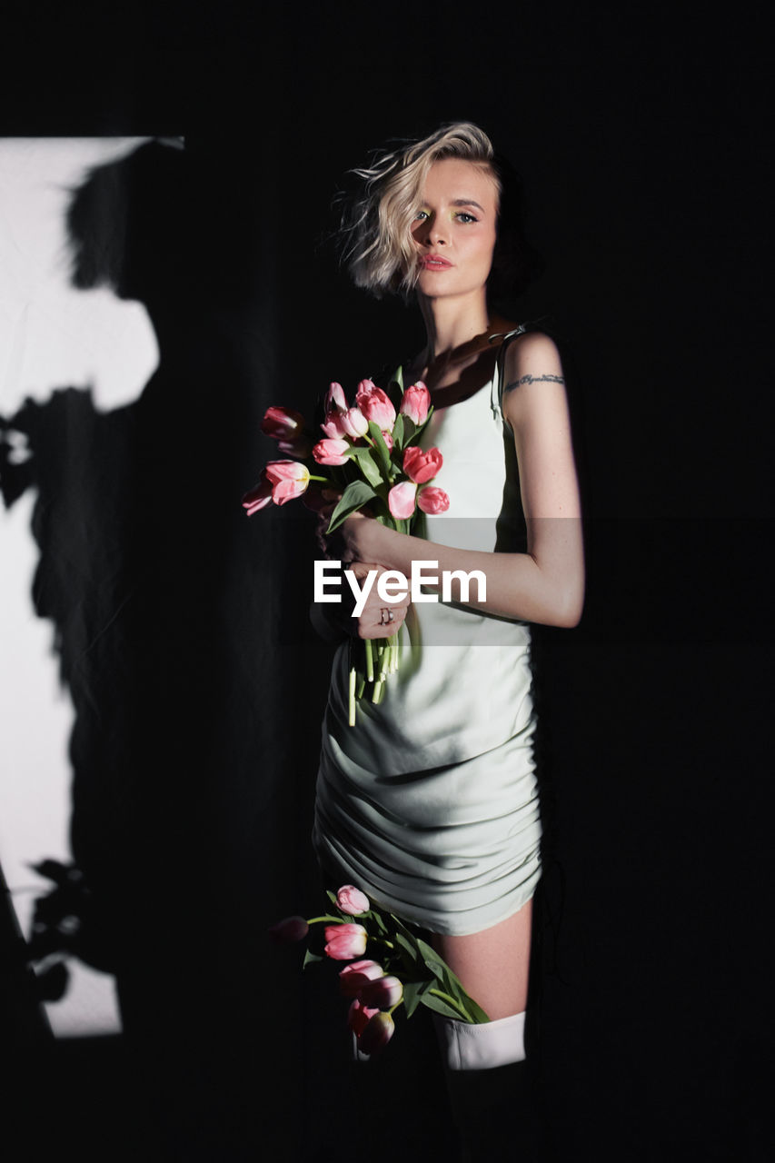 Beautiful stylish young woman with tulips in the spotlight