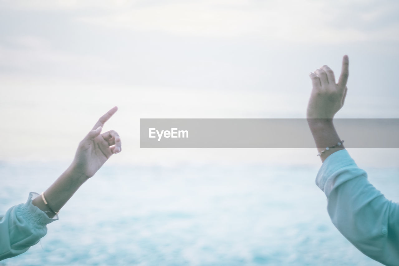 Low angle view of man hand against sea against sky