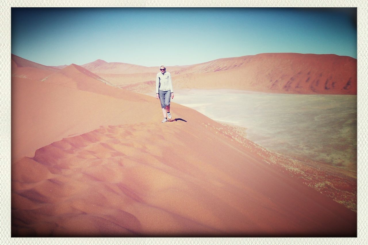 Woman walking in desert during sunny day