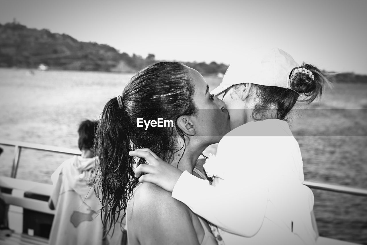 Mother kissing her daughter by sea