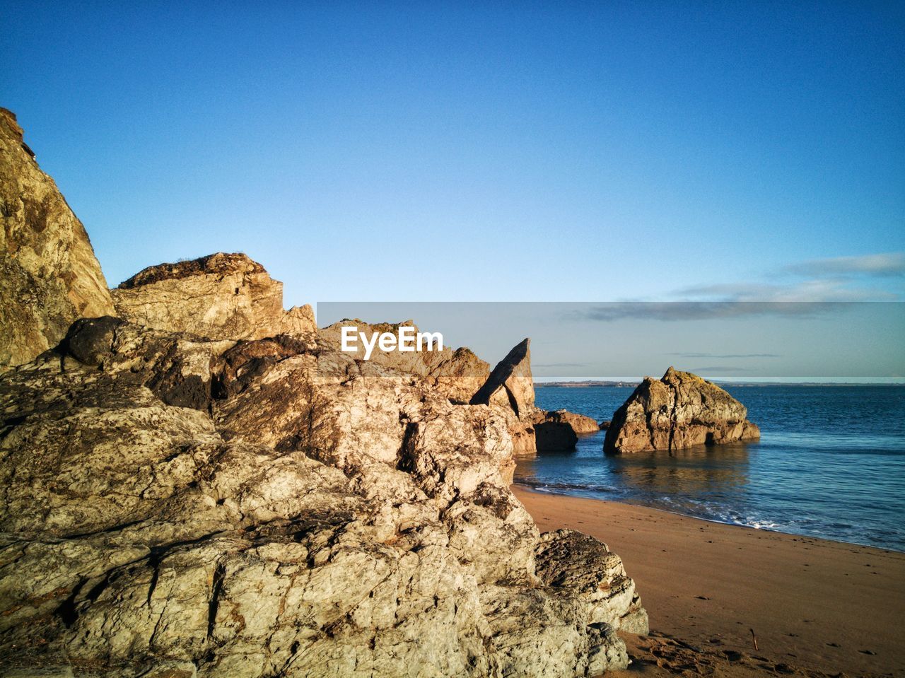 Rock formation on beach against clear blue sky