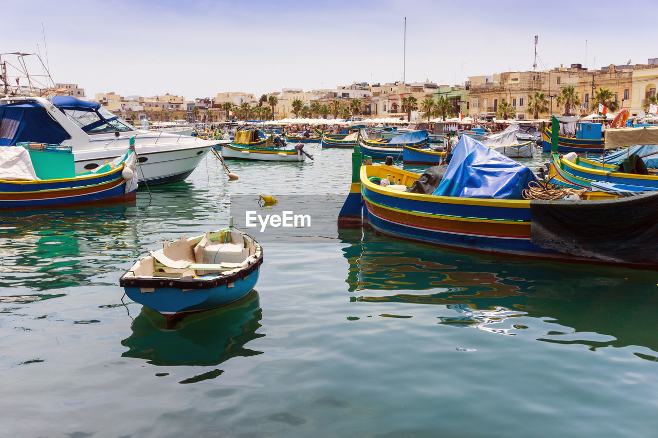 Boats moored at harbor against sky