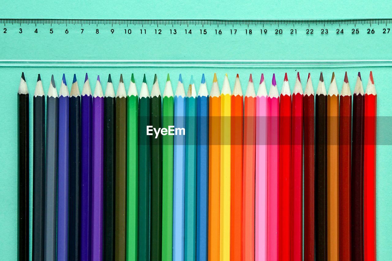 Close-up of colored pencils on table by ruler