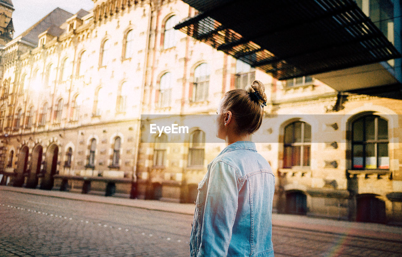 REAR VIEW OF A MAN WALKING IN CITY