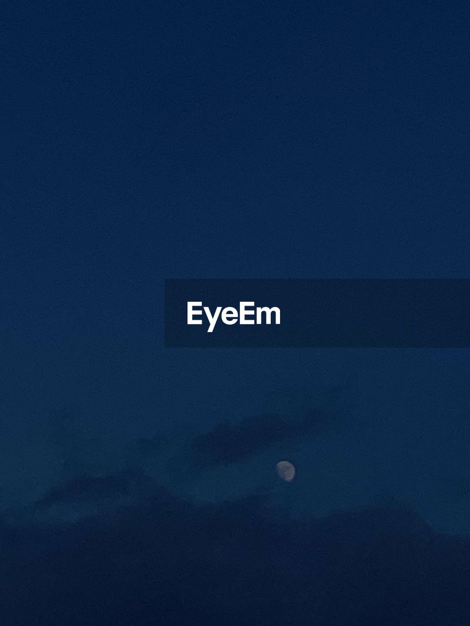 LOW ANGLE VIEW OF MOON AGAINST BLUE SKY AT NIGHT