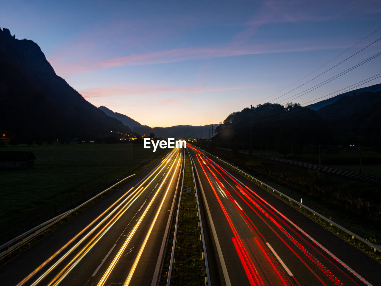 Light trails on road against sky during sunset