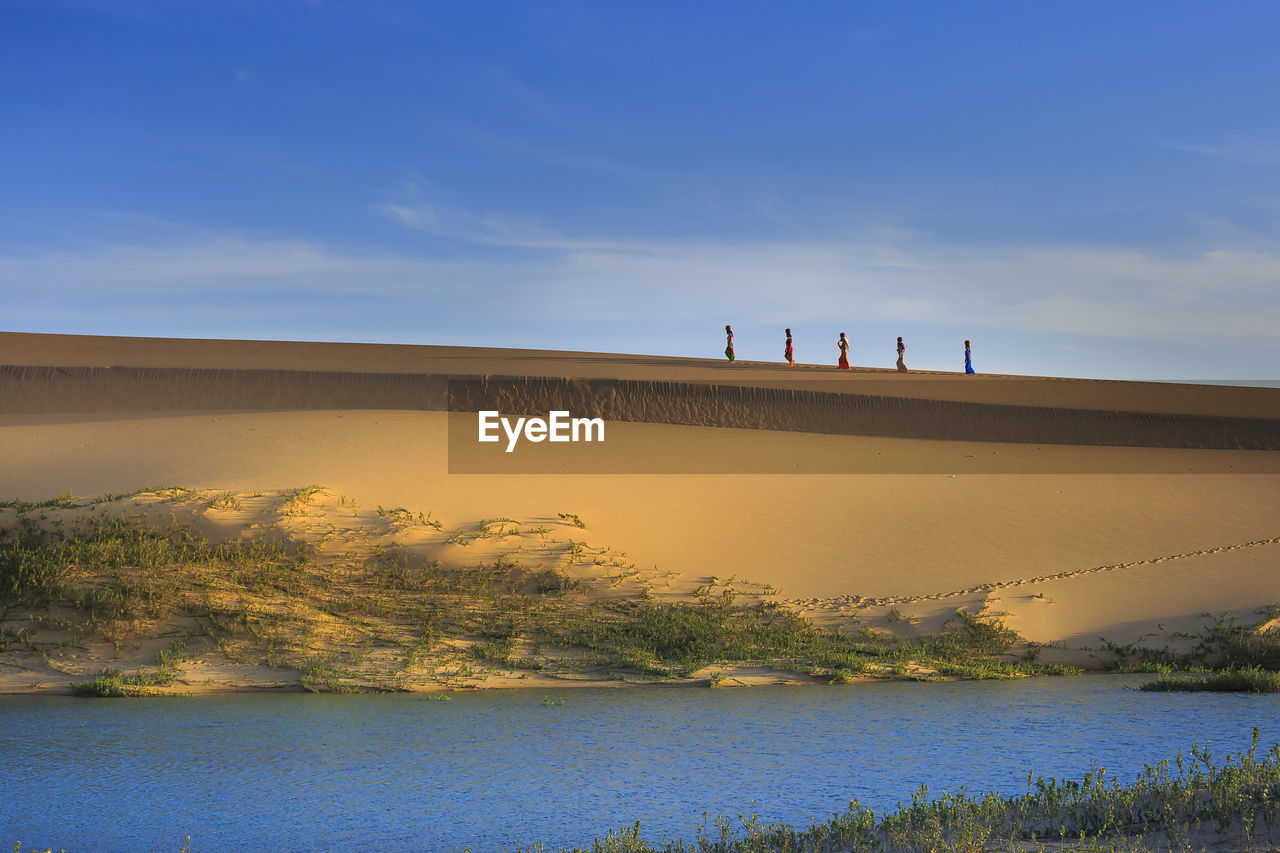  view of women carrying water on sand dune