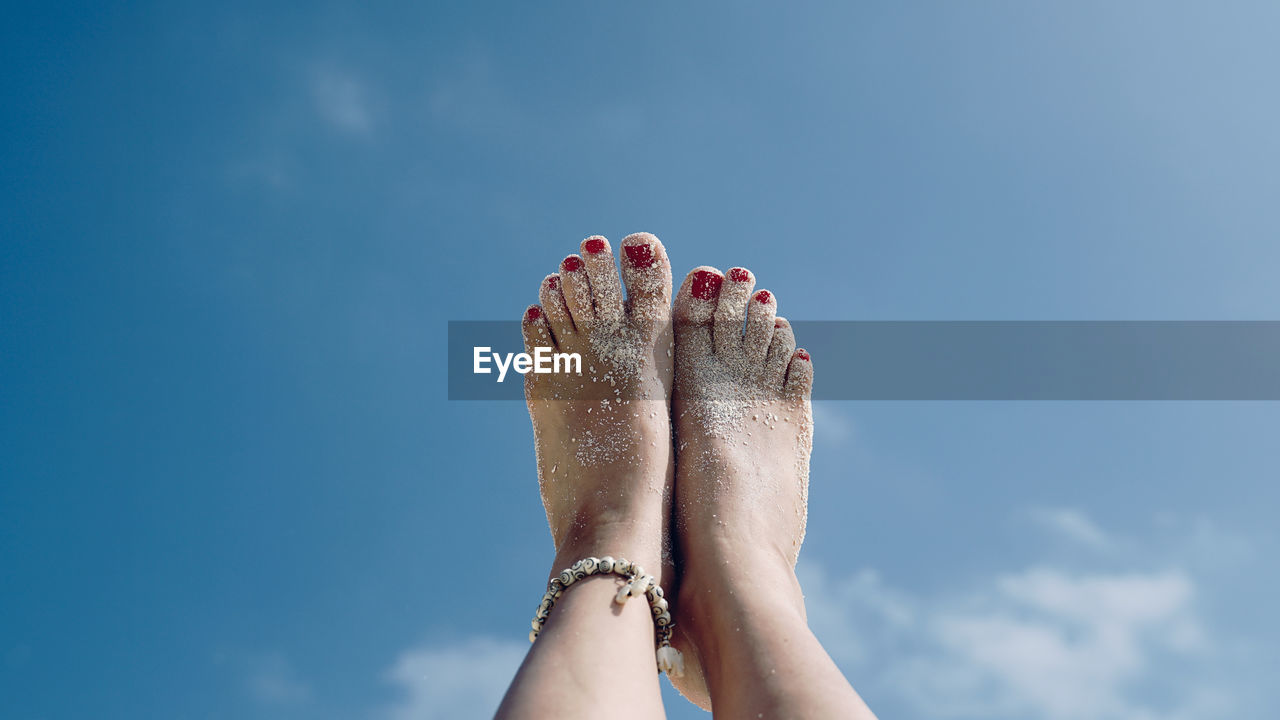 Low angle view of woman feet against sky