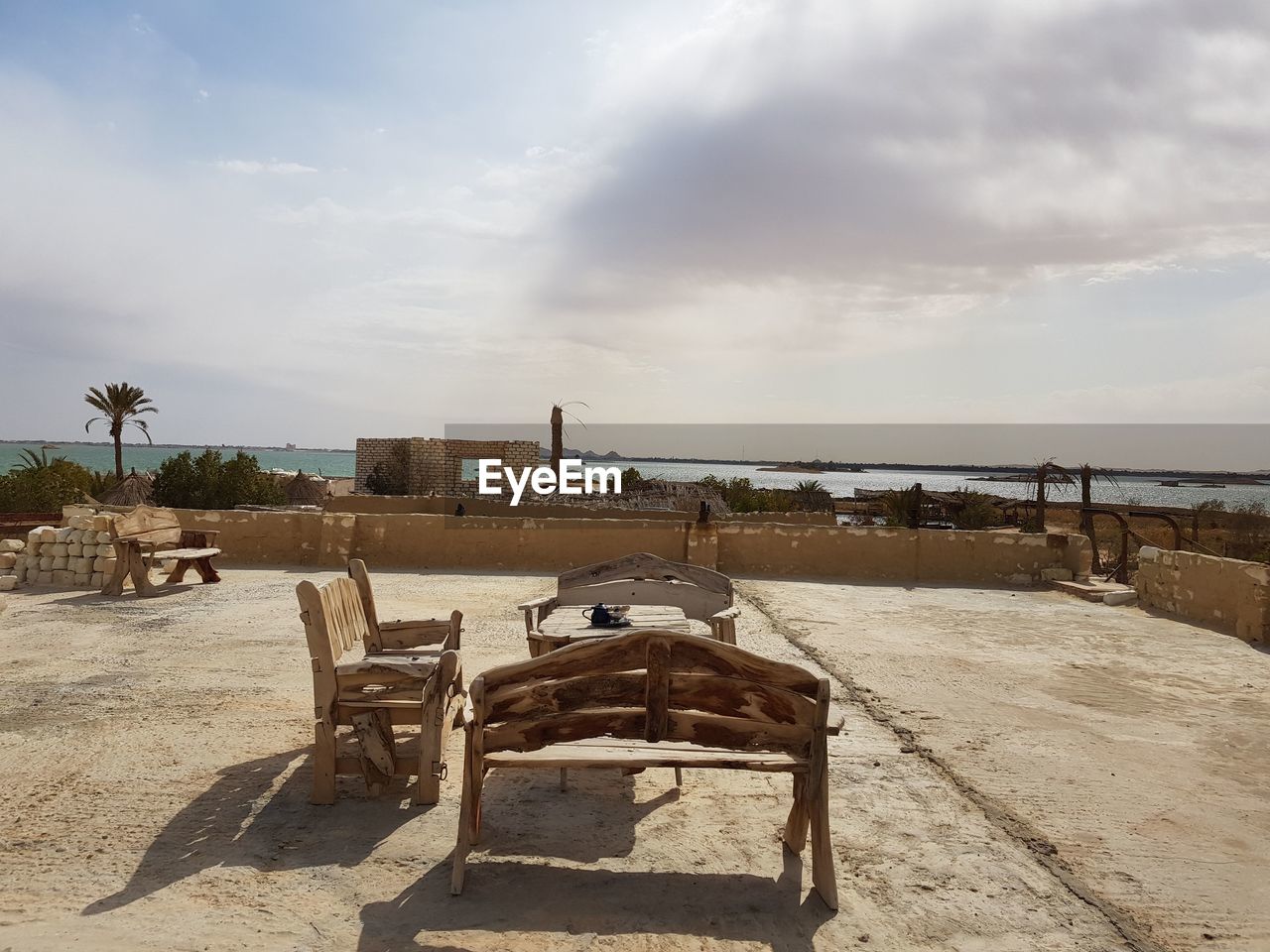 ABANDONED CHAIR ON SHORE AGAINST SKY