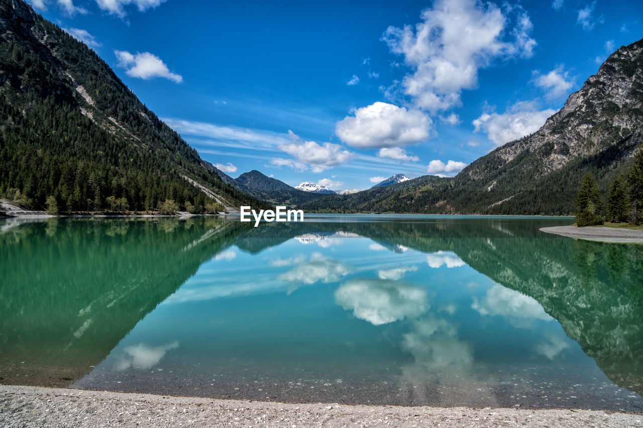 Scenic view of lake and mountains against blue sky