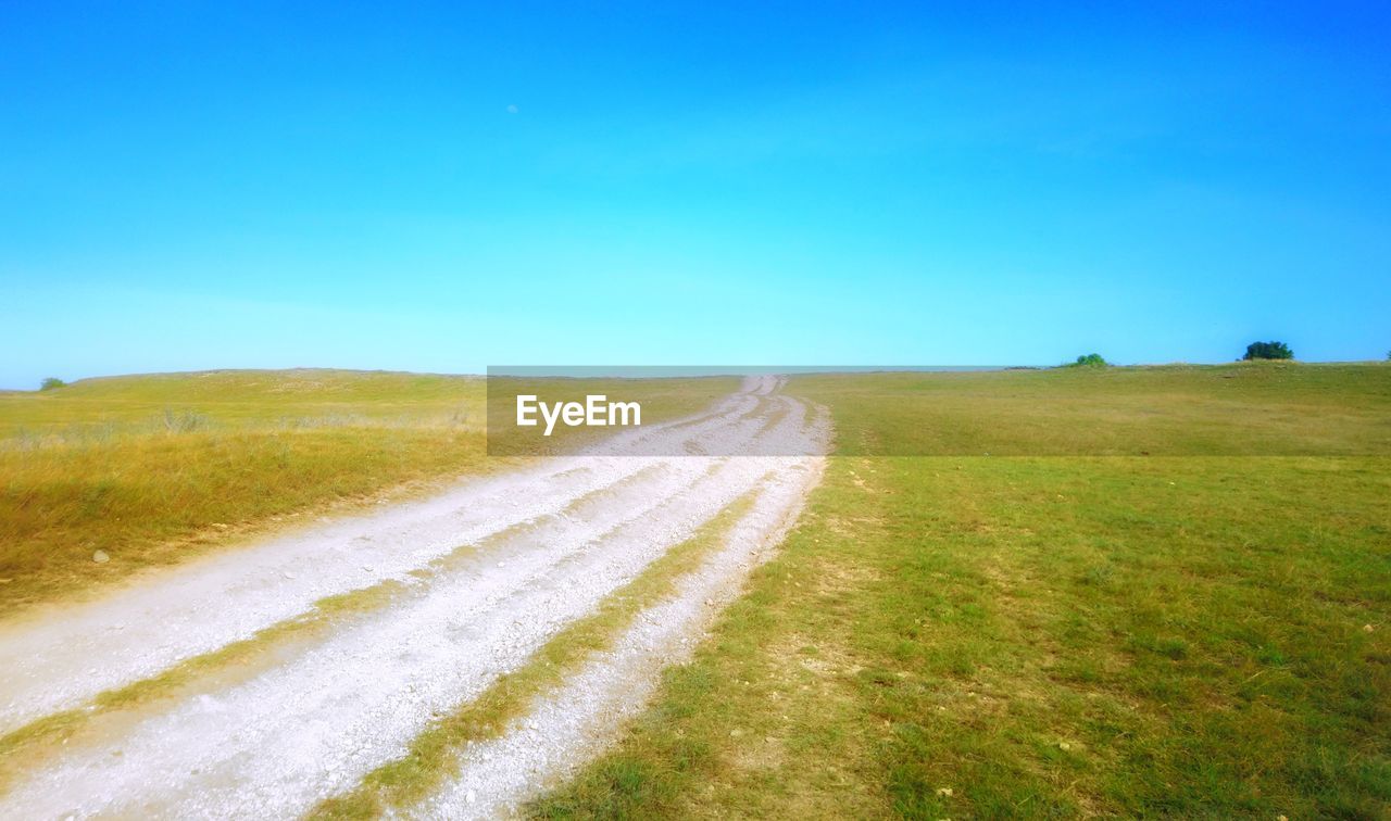 ROAD AMIDST FIELD AGAINST CLEAR SKY