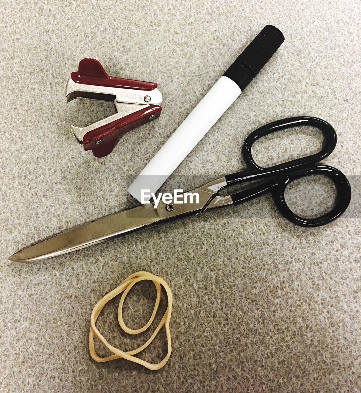 High angle view of pen with stapler and rubber band by scissors on table