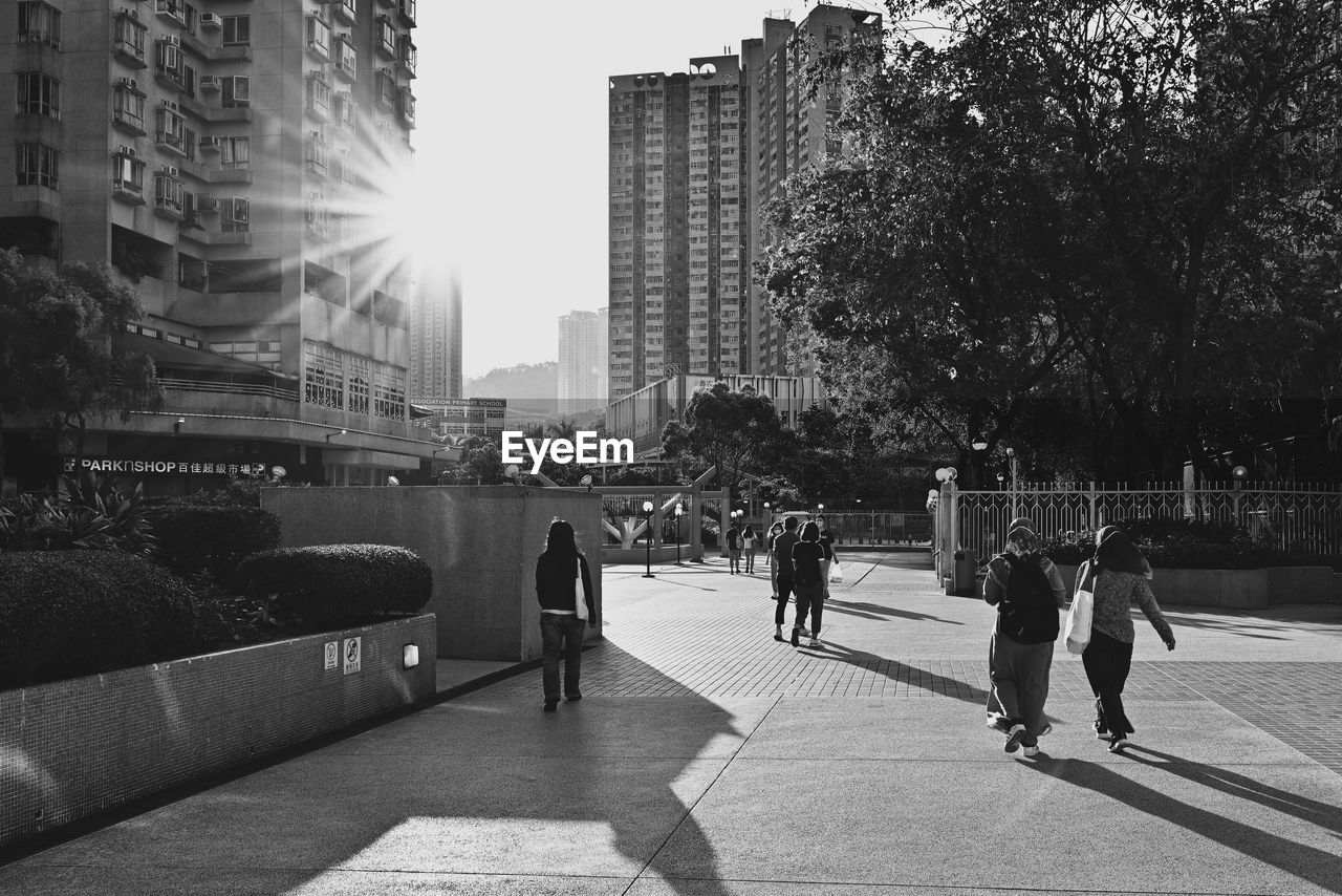 People on footpath by buildings in city