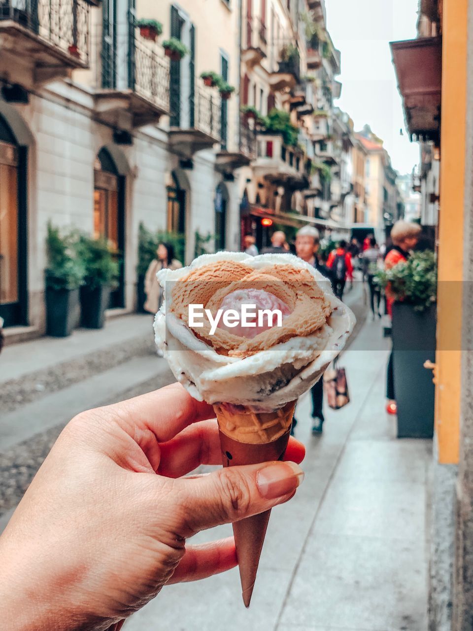 Hand holding ice cream cone in city