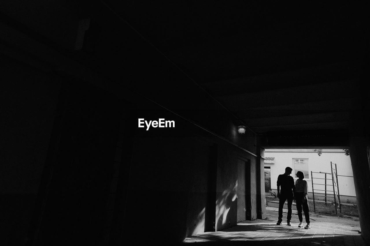 Full length of silhouette couple walking in tunnel