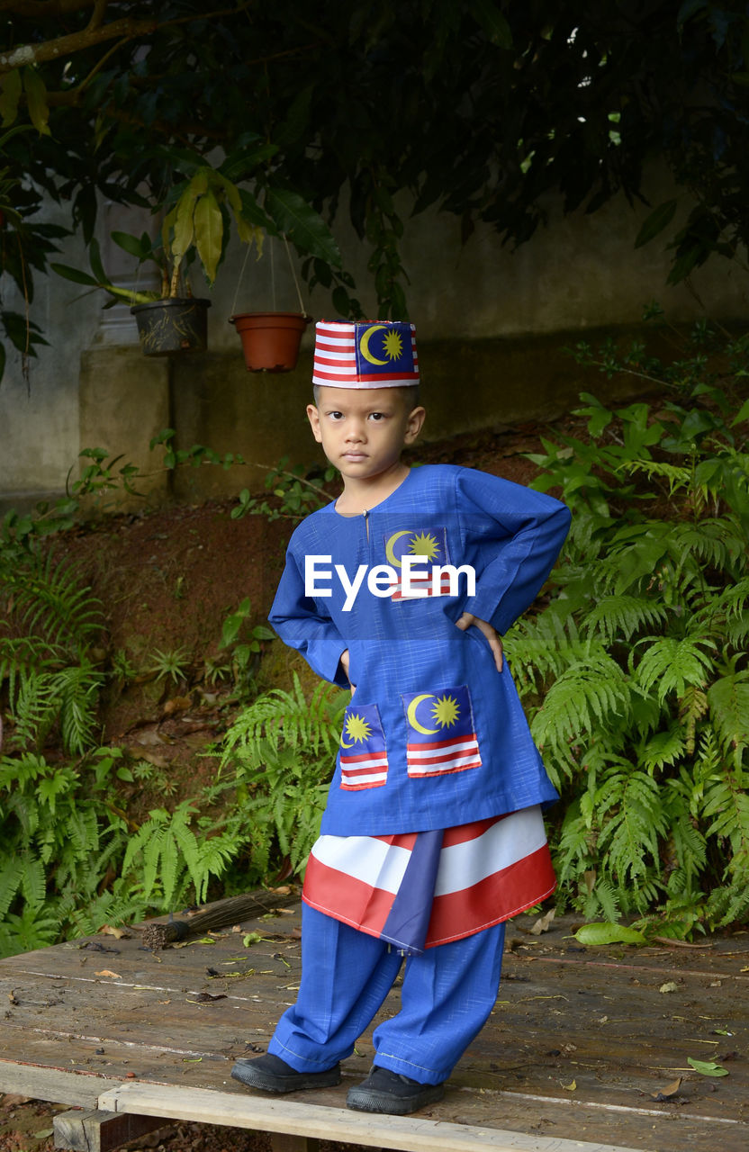 Portrait of boy standing by plant