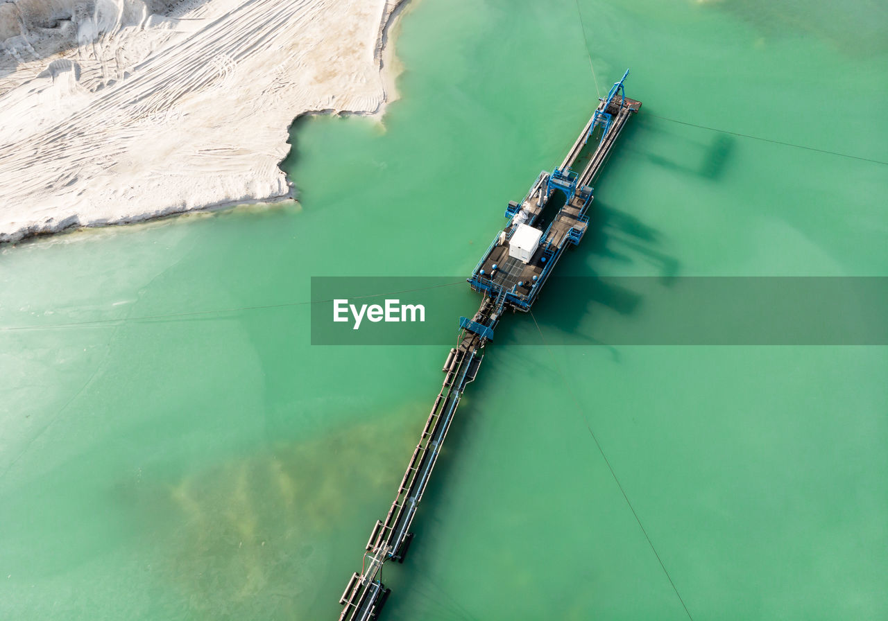 Aerial view of the long boom of a suction excavator in a quartz quarry for the excavation of sand.