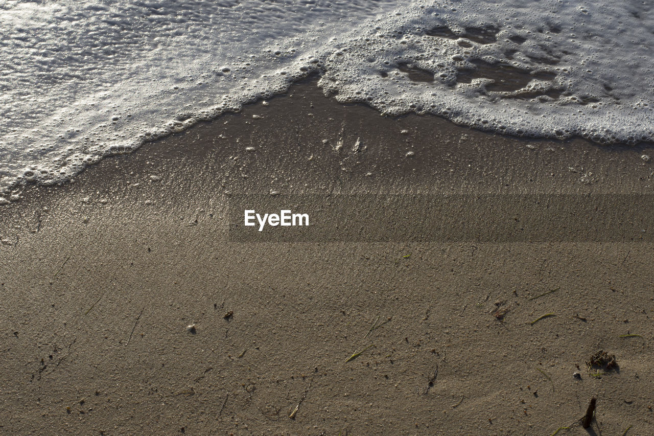 HIGH ANGLE VIEW OF FOOTPRINTS ON WET SHORE
