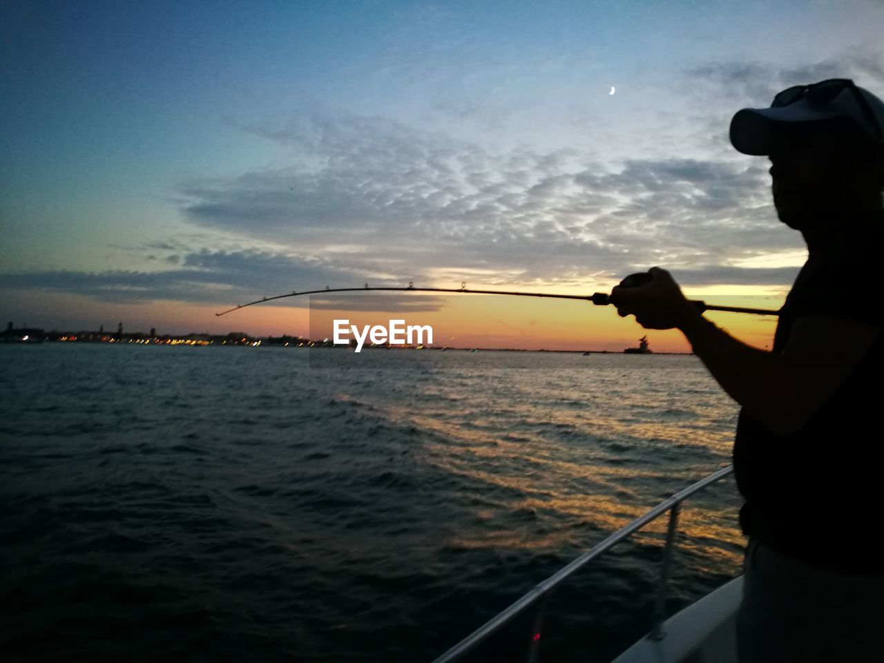 SILHOUETTE MAN HOLDING BOAT SAILING ON SEA AGAINST SKY DURING SUNSET