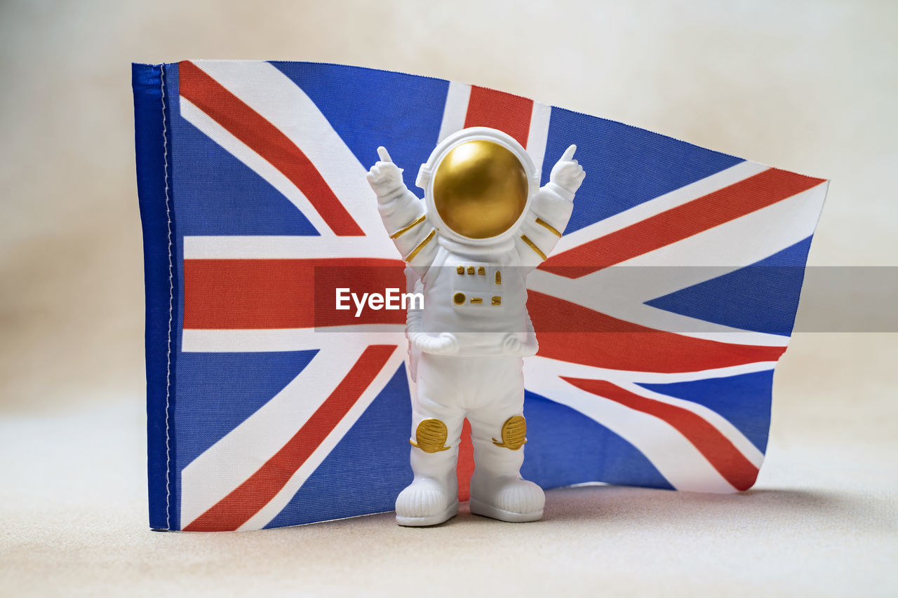 Happy astronaut standing with raised hands on uk flag background
