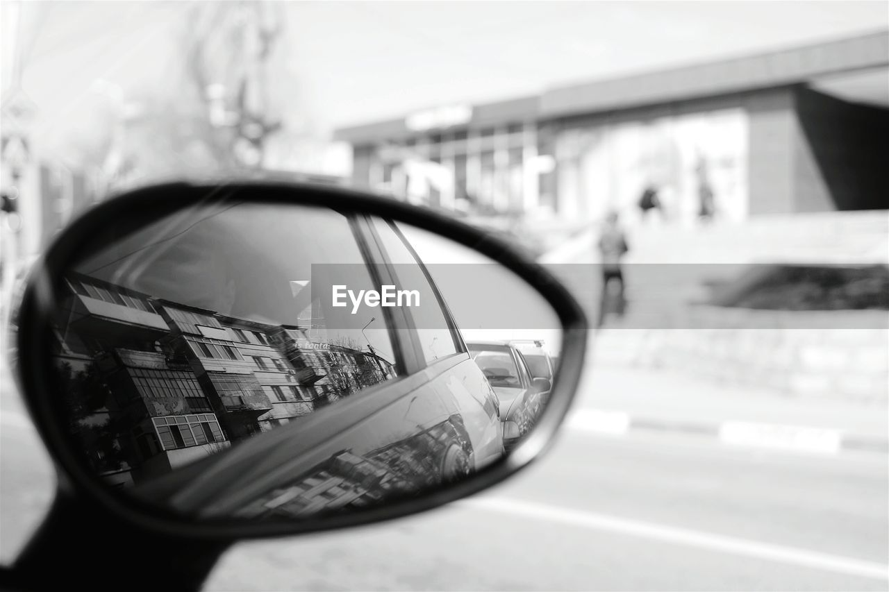 Reflection of buildings in side-view mirror of car