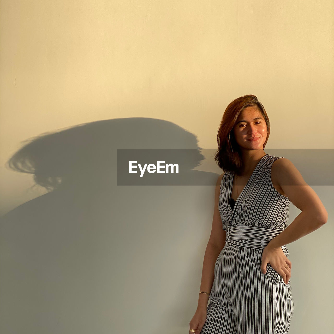 Portrait of smiling young woman standing against wall