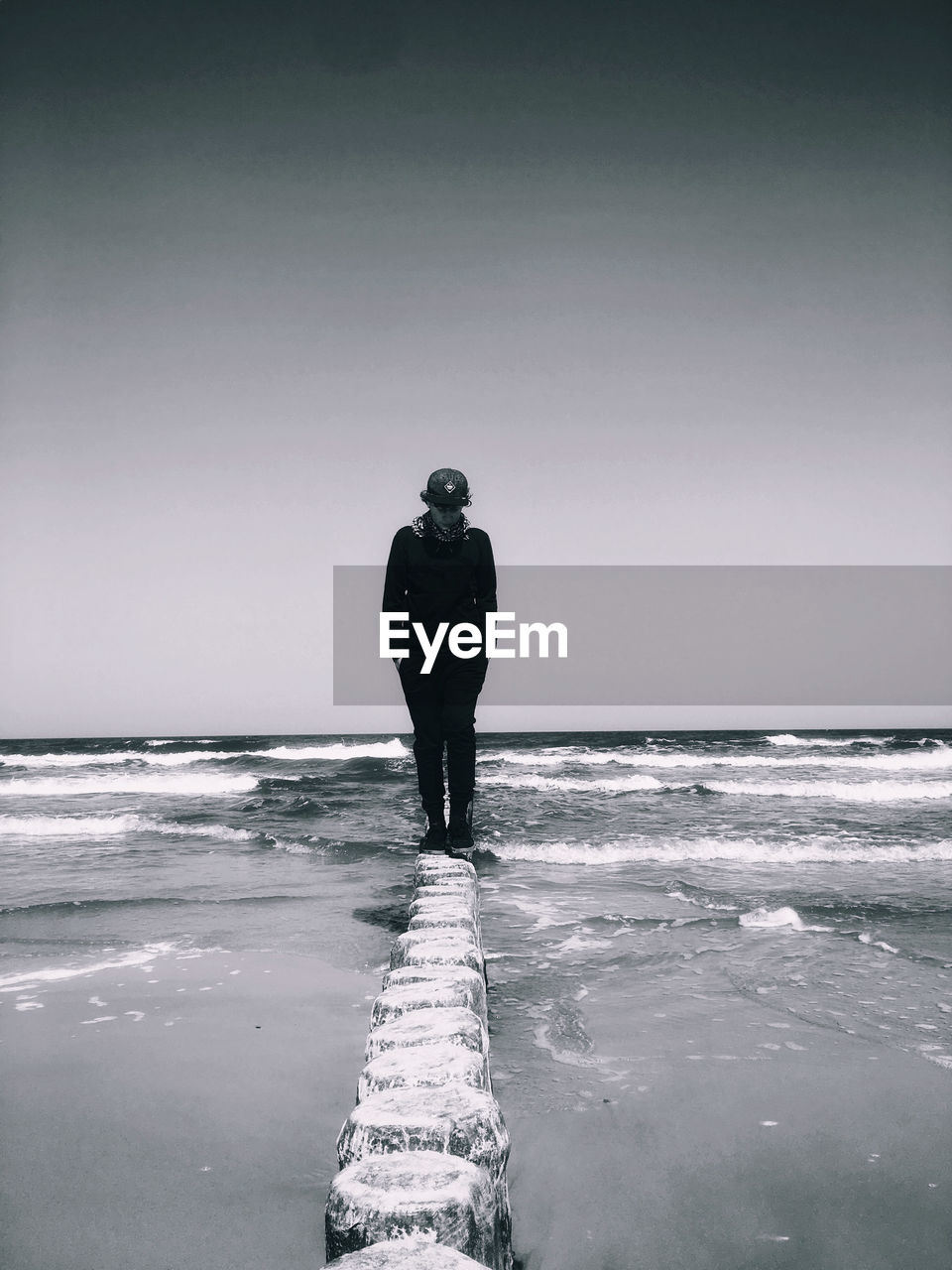 Teenage boy standing at beach against sky