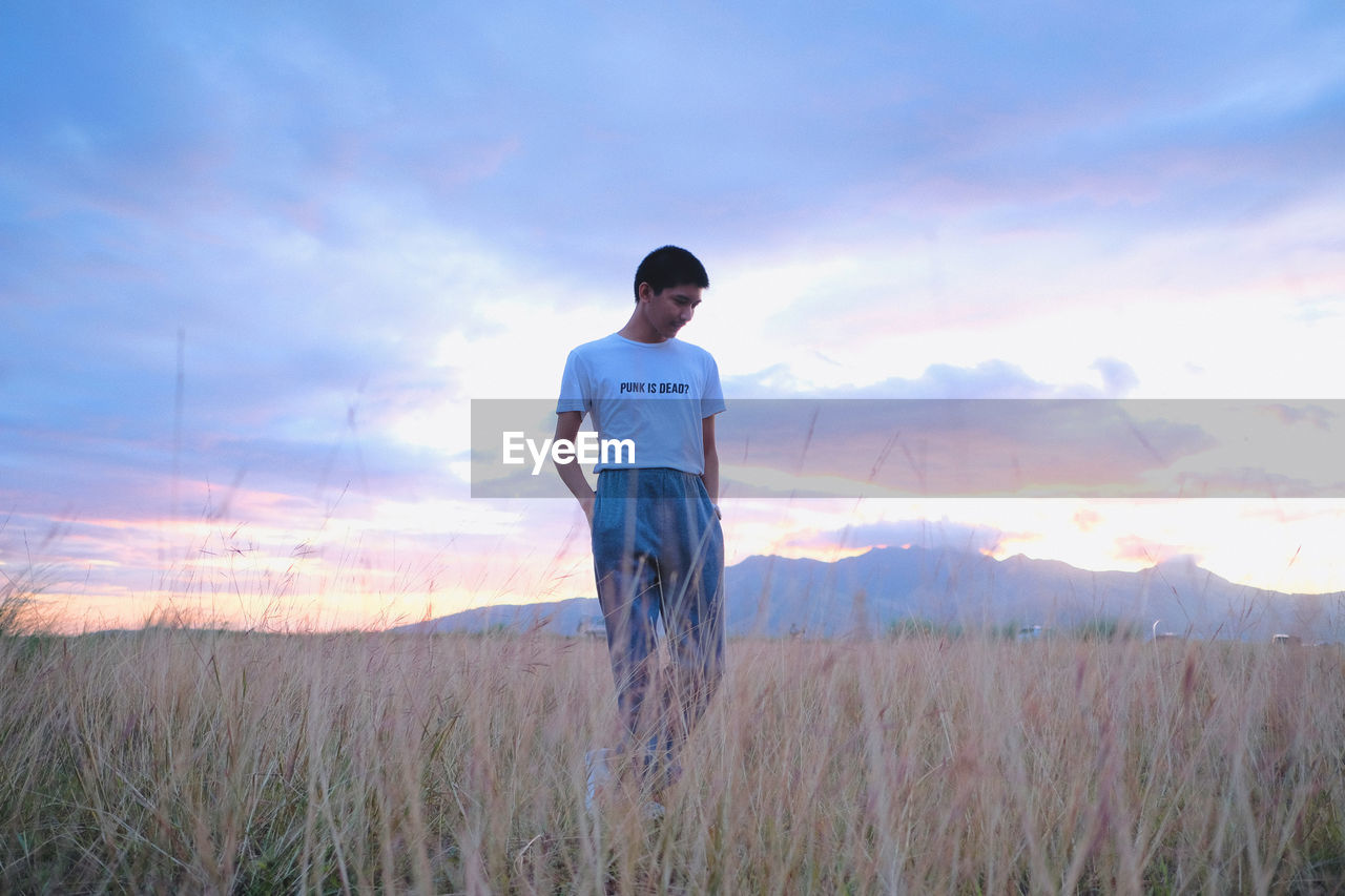 Man standing on field against sky during sunset