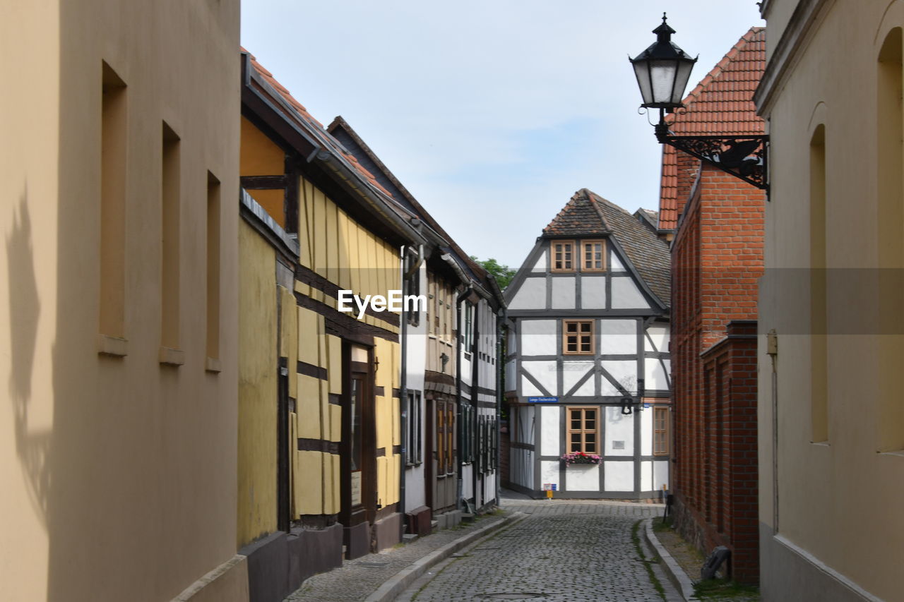 ALLEY AMIDST BUILDINGS IN CITY AGAINST SKY