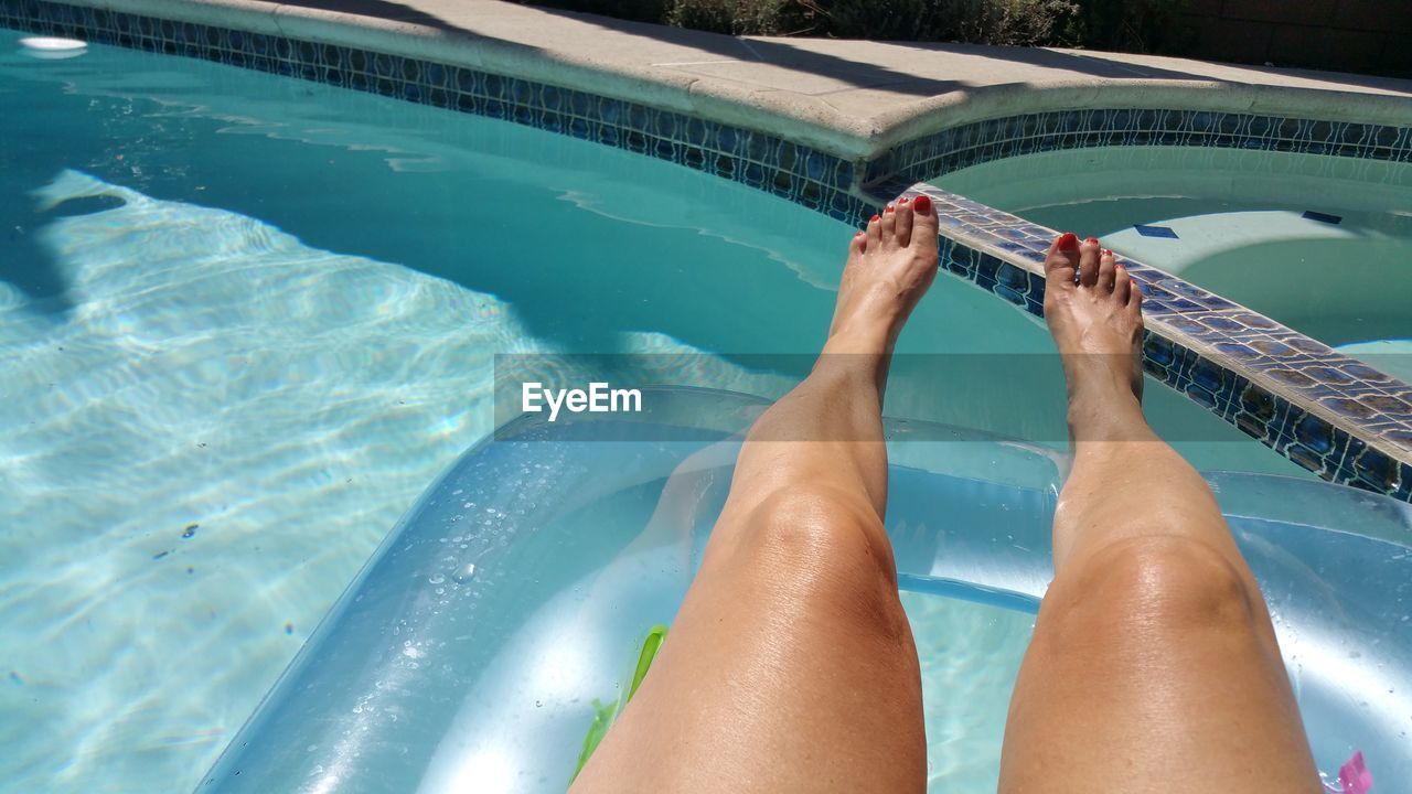 Low section of woman floating on swimming pool
