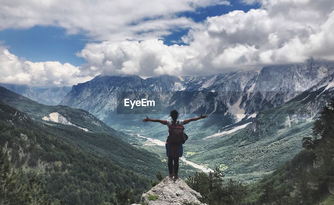 Rear view of woman standing on rock against mountains