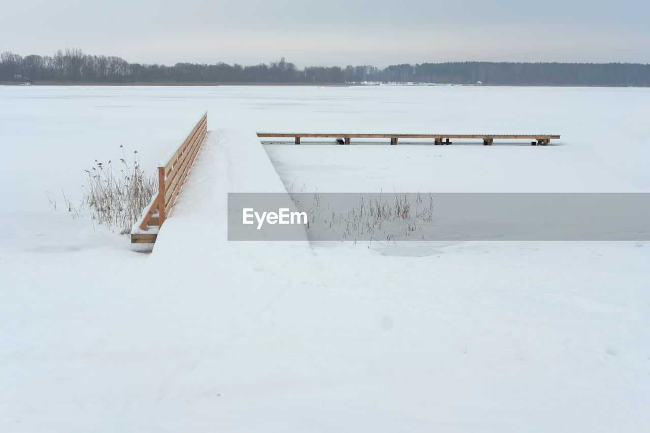 Scenic view of snow covered jetty by lake