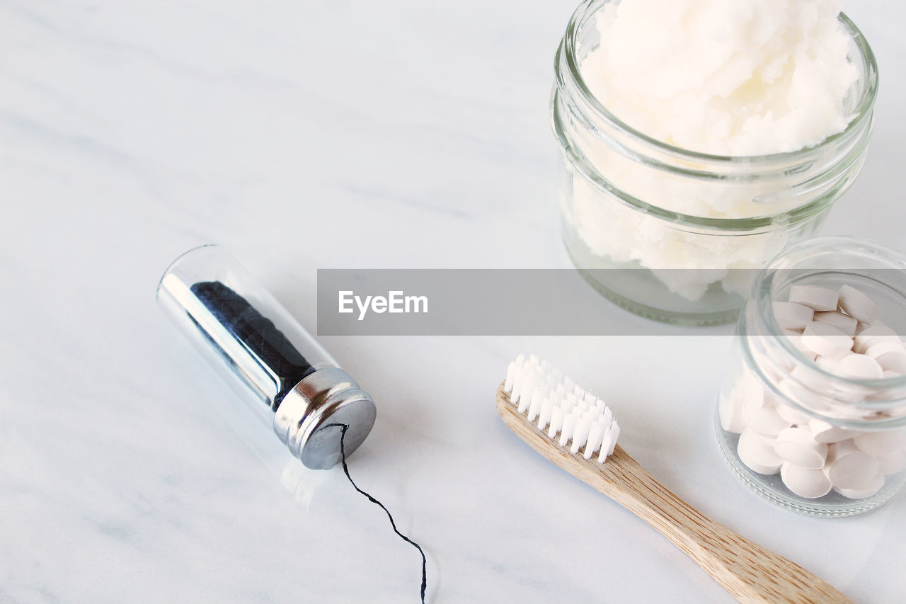 High angle view of toothbrush with toothpaste and medicines on white background