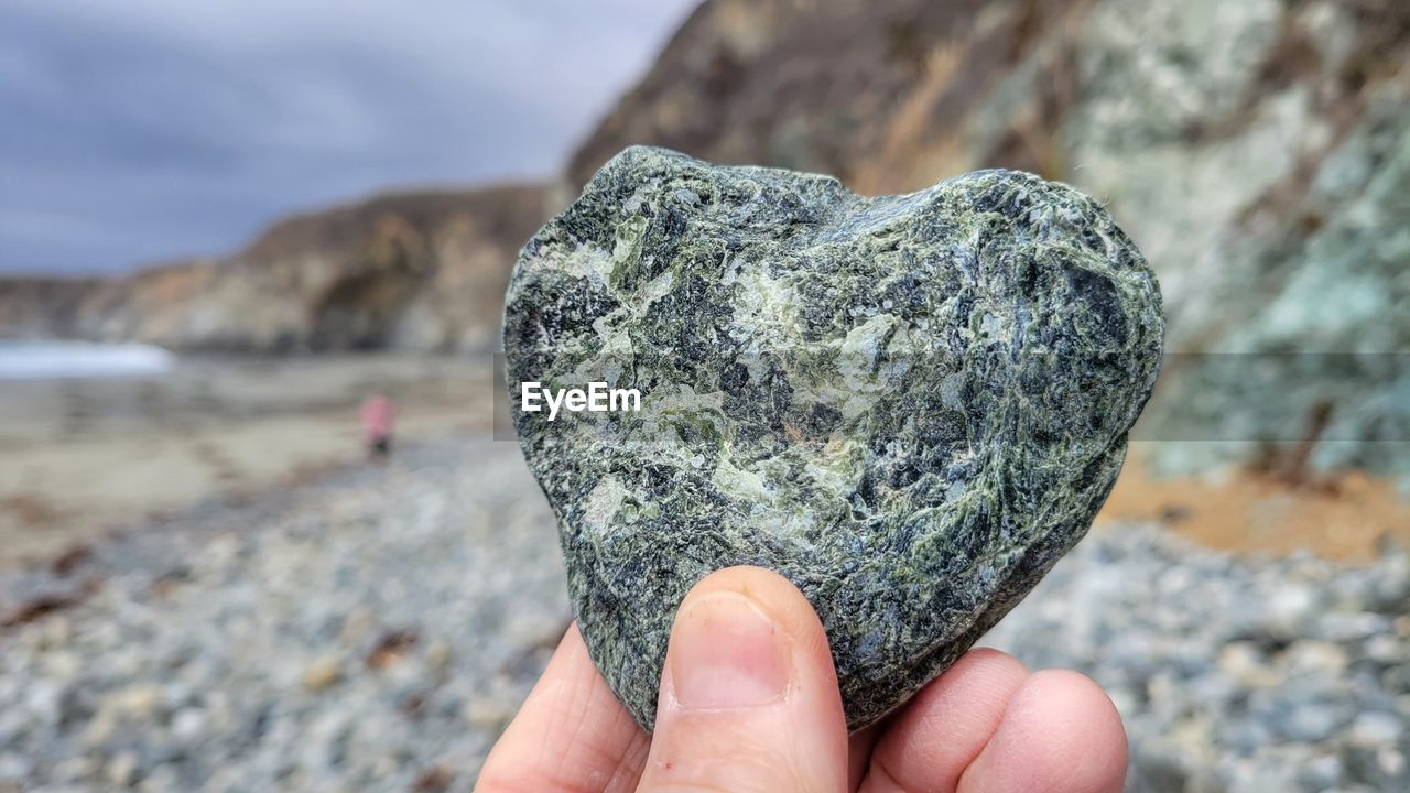 CLOSE-UP OF PERSON HAND HOLDING ROCK