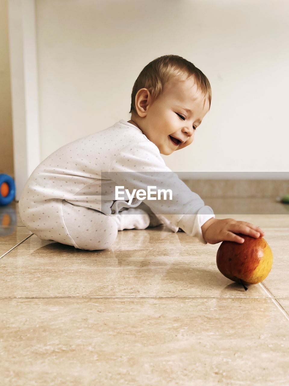 Portrait of cute baby boy sitting on hardwood floor at home