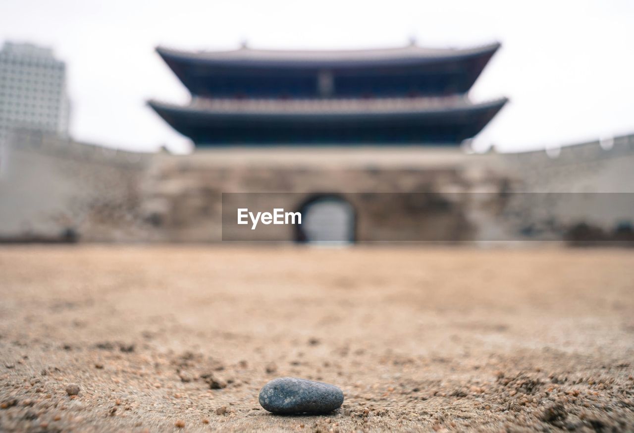 Surface level of pebble with blurred built structure in distance