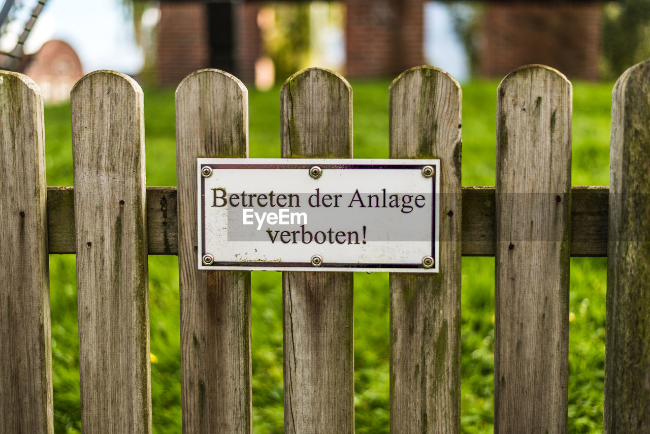 Close-up of warning sign on wooden fence