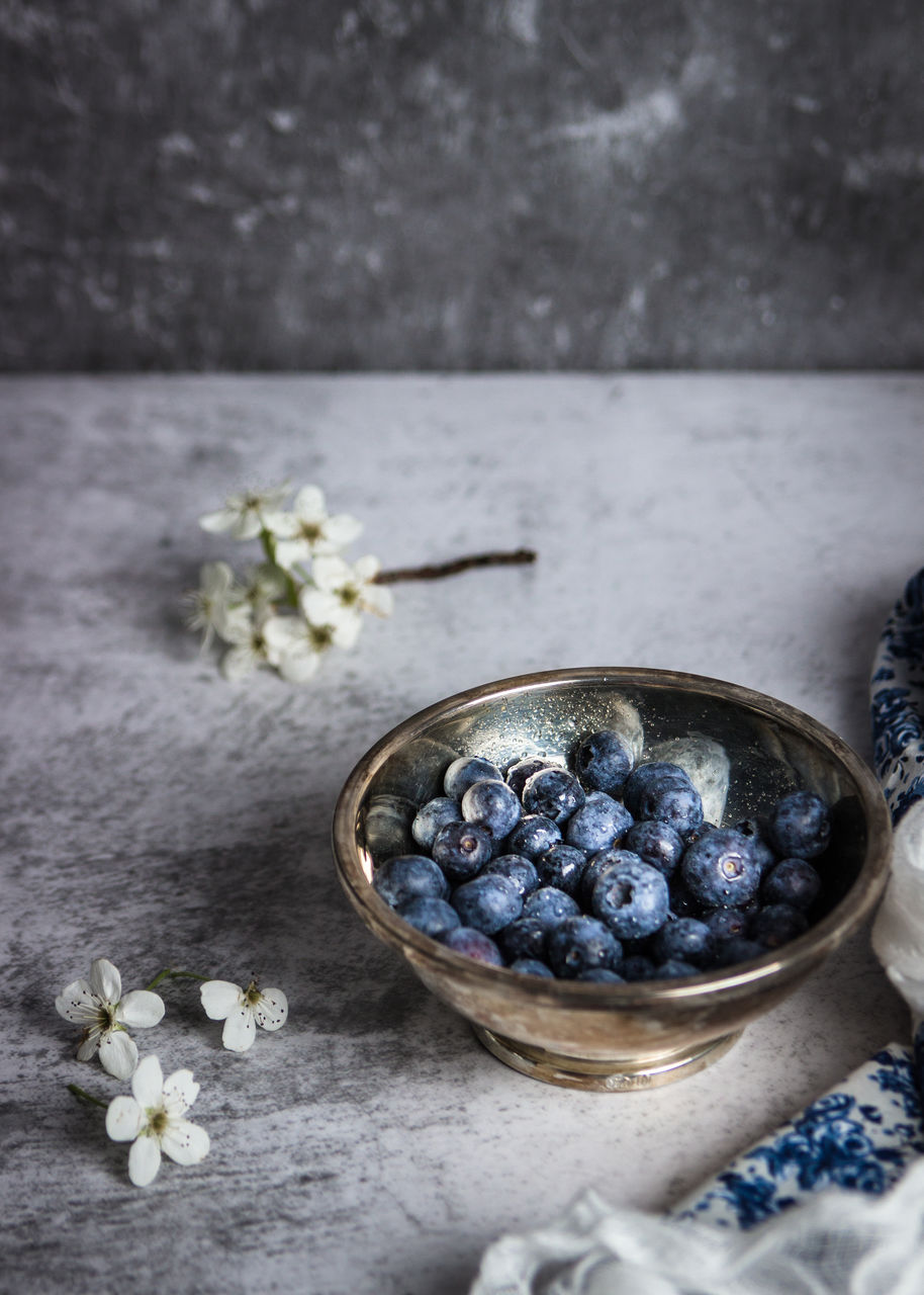 Bowl with fresh blueberry on table